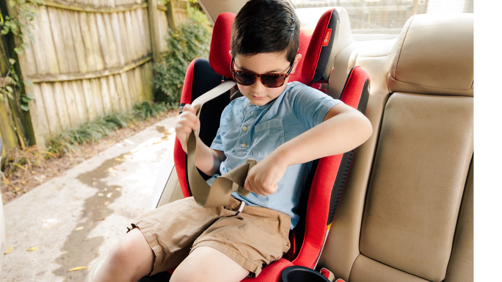 A school-age child buckling the seat belt in a high-back booster