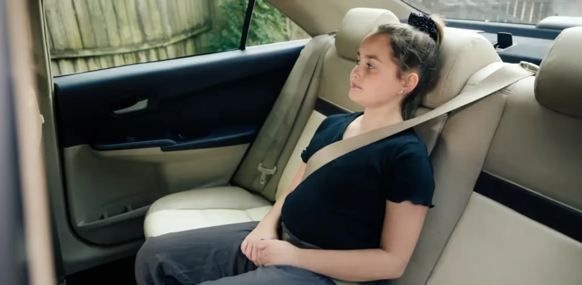 A school-age child sitting upright with the vehicle seat belt correctly positioned